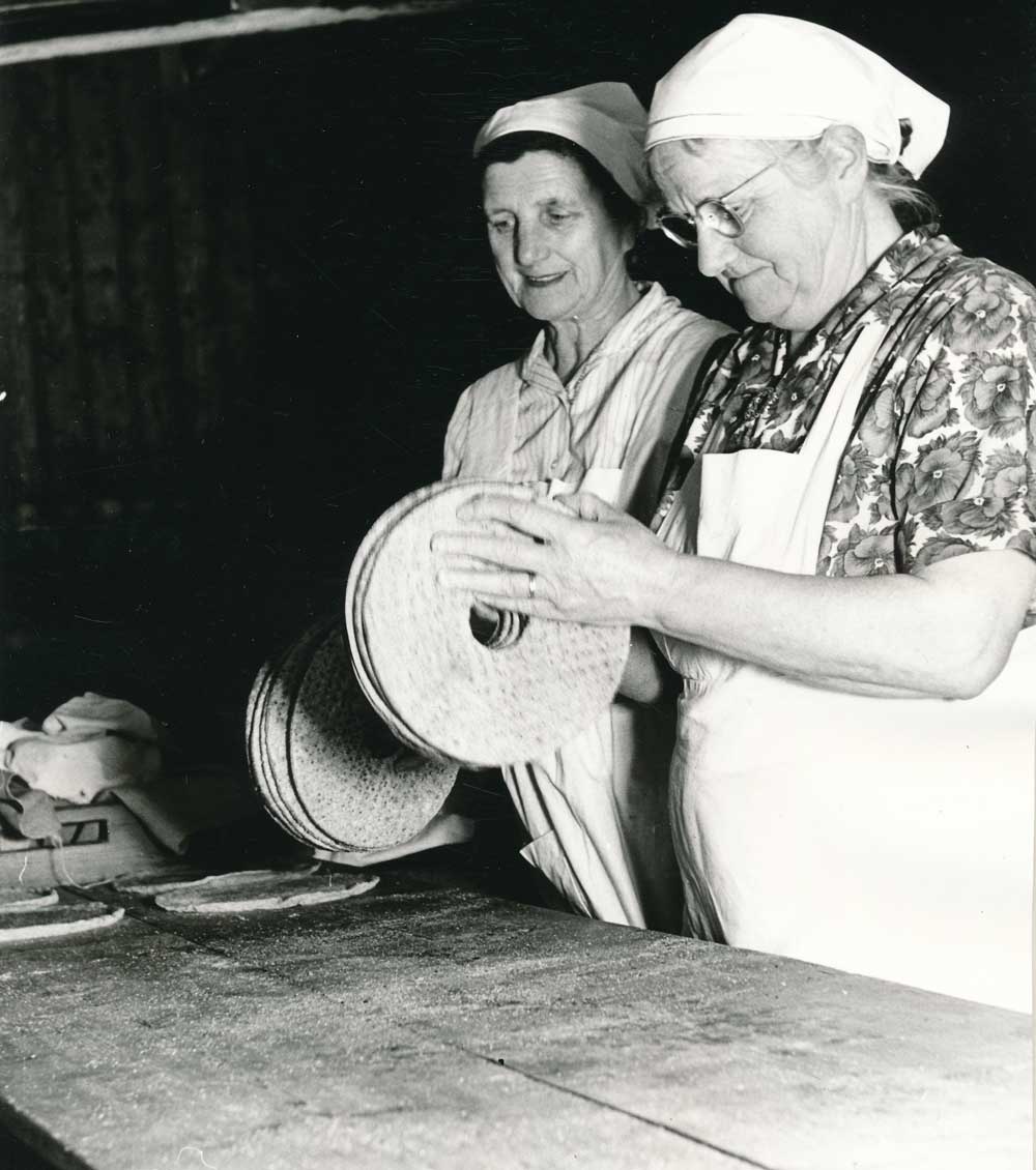 Två kvinnor som bakar bröd vid ett bakbord.