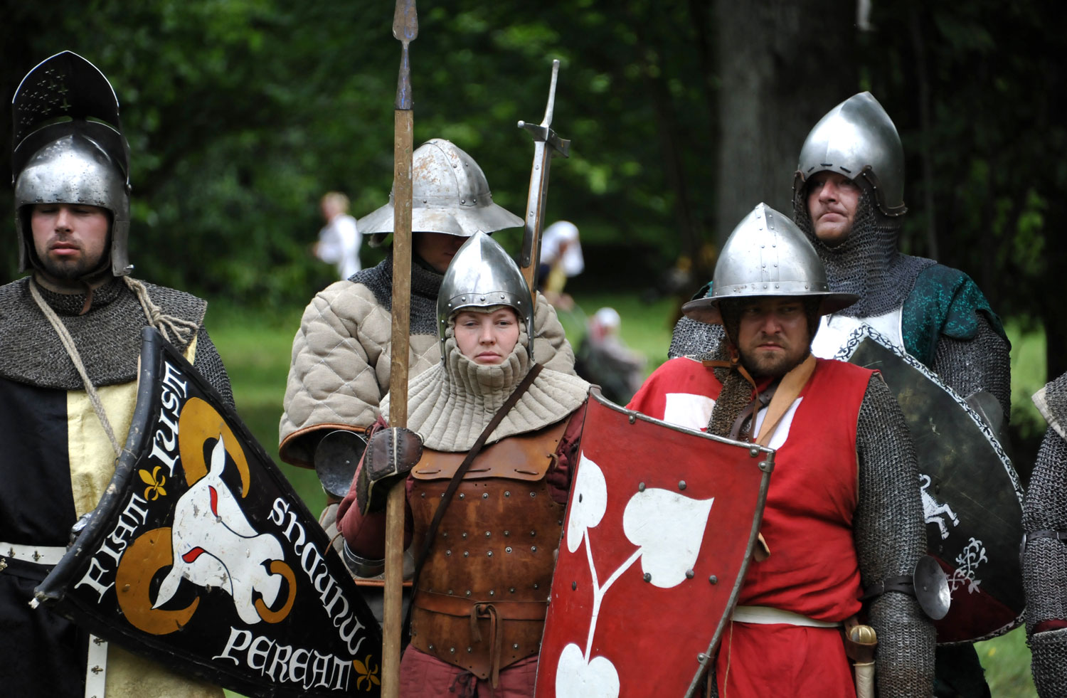 Människor i medeltida stridskläder och vapen.
