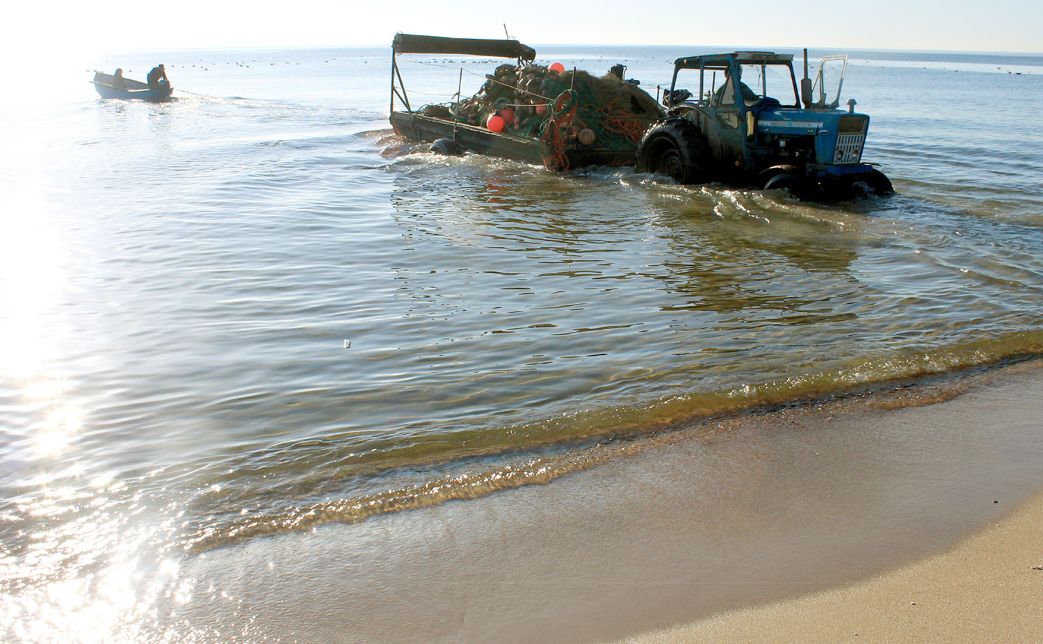 Traktor och båtar i vattenbrynet.