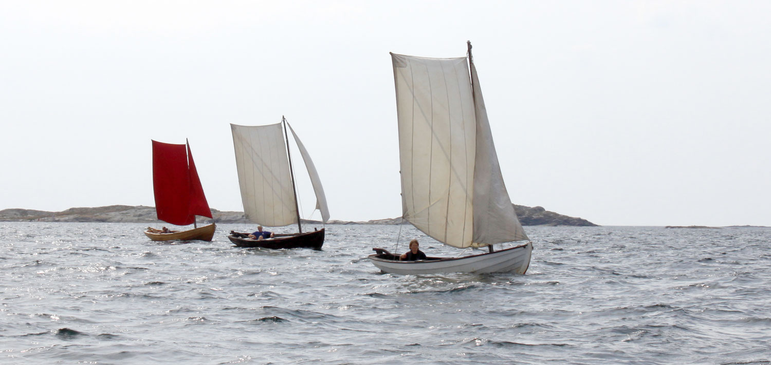 Tre båtar seglar med hissade segel.