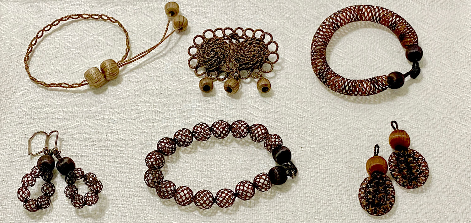 Örhängen, brosch, halsband och armband tillverkade av mörkbrunt hår.