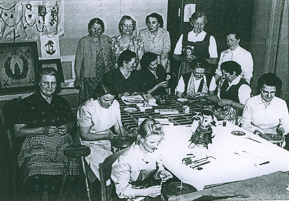 Kvinnor som handarbetar runt ett stort bord.