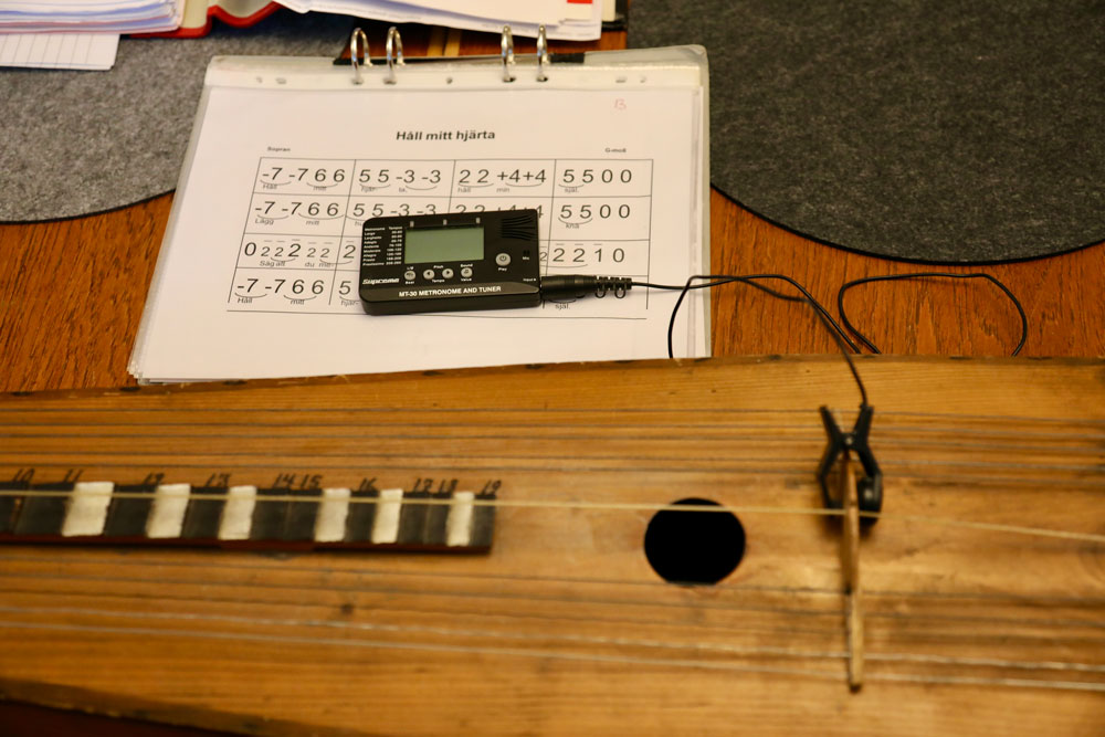 Närbild på noter med siffror som ligger framför ett psalmodikon.