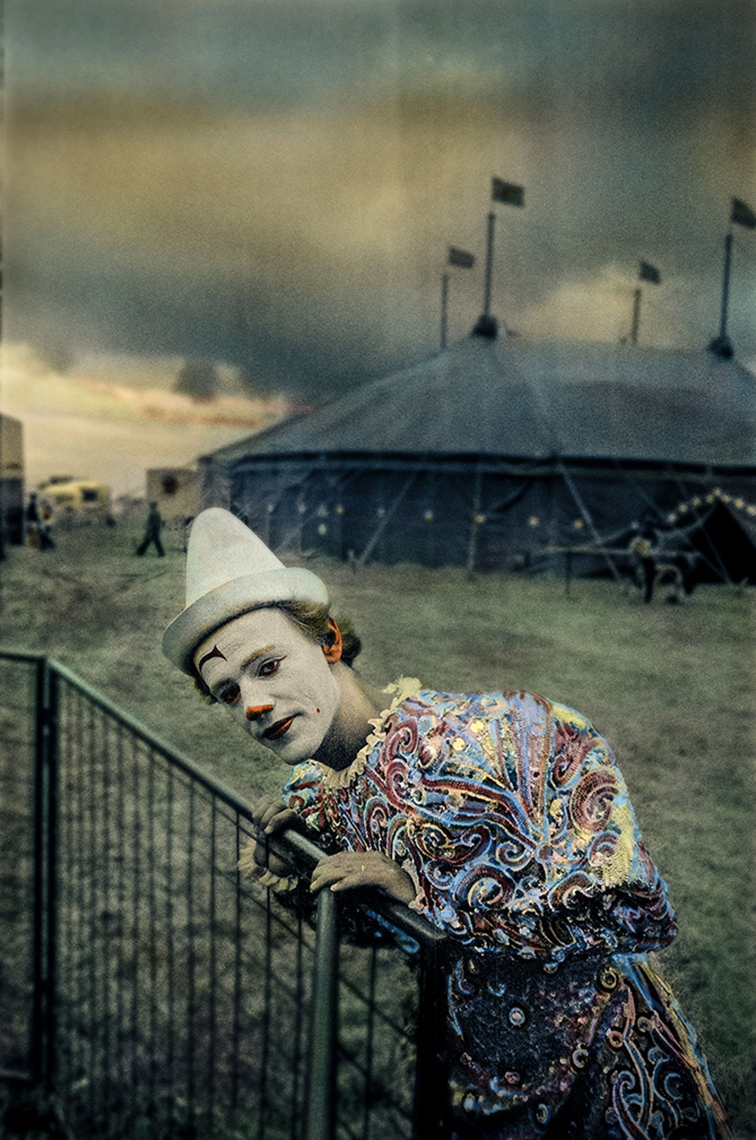 Vitsminkad clown fotograferad utanför cirkustält.